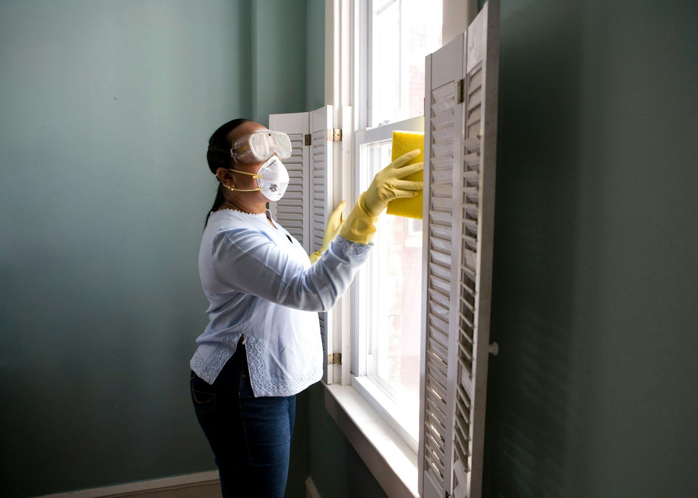 Professional cleaner detailing window shutters and frames